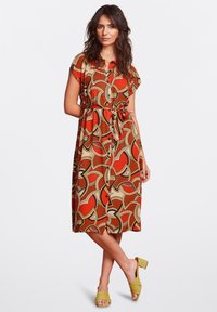 Red and brown patterned dress with short sleeves, a waist tie, and a midi length. Accompanied by yellow block-heeled shoes.