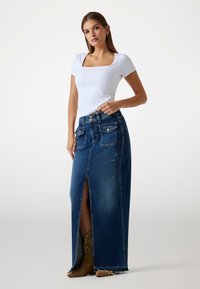 Denim maxi sukně s předním rozparkem, modrý ombre, distressed detaily, design s pěti kapsami, doplněná o přiléhavý bílý top s krátkými rukávy.