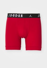 Røde boxer briefs lavet af glat stof med en sort talje, der har "JOA" og "DAN" i hvid, akcentueret med et Jordan-logo.
