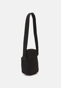 Borsa a spalla in tessuto nero con forma rettangolare, un ampio manico regolabile e una tasca laterale con zip per riporre gli oggetti.