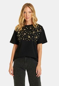 Zwarte katoenen t-shirt met metallic gouden bloem- en ronde versieringen aan de voorkant, met korte mouwen en een losse pasvorm.