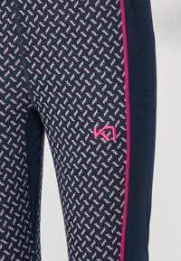Marineblå leggings med et rosa zigzag-mønster, med en rosa sidebesetning og en liten logo på den nederste delen av benet. Myk og elastisk stoff.