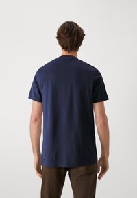 Námořnická modrá bavlněná tričko s klasickým kulatým výstřihem a krátkými rukávy, s hladkým povrchem a pohodlným střihem.