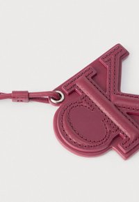 Porte-clés en cuir rose foncé cousu avec de grandes lettres en relief "C" et "K" attachées à une lanière en cuir assortie.