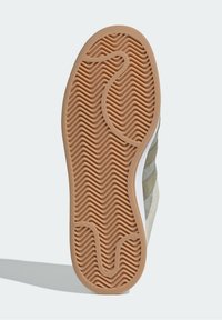 Schuhsohle mit einem strukturierten Gummiboden und einem wellenförmigen Muster. Der obere Abschnitt enthält Akzente aus hellgrauem und cremefarbenem Wildleder.