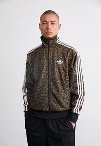 Hnedá športová bunda na zips s leopardím vzorom a bielymi pruhmi, čiernymi akcentmi, vysokým golierom a bočnými vreckami.