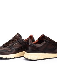 Zapatillas de cuero marrón con paneles texturizados, puntera redonda, diseño con cordones y una suela de goma crema con un patrón geométrico.