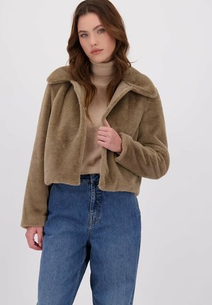 Korte beige nepleren jas met een brede kraag, subtiele glans en drukknoopsluiting, gecombineerd met lichtblauwe hoogwonderende jeans.