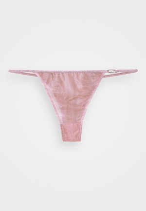 Cueca fio dental de veludo rosa com tiras laterais finas, apresentando um pequeno detalhe prateado na cintura. Textura suave com um design minimalista.