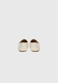 Beige leather shoes with a rounded back. Features minimal stitching and a slightly textured surface. Flat sole for comfort.