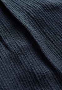 Tekstureret mørkeblå stof med et krøllet mønster; blødt, vævet materiale med et subtilt gitterlignende design i forskellige nuancer.