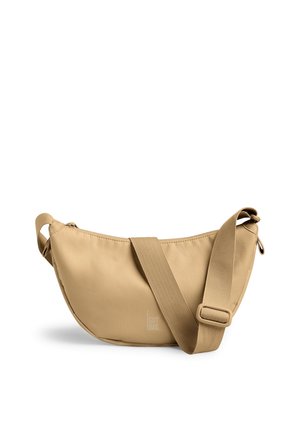 Sac bandoulière en tissu beige en forme de croissant avec une large sangle réglable et un logo discret "GOT BAG" au centre devant.