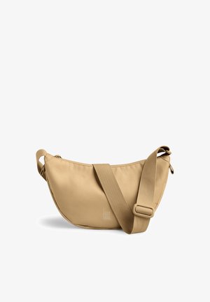 Sac bandoulière en tissu beige en forme de croissant avec une large sangle réglable et un logo discret "GOT BAG" au centre devant.