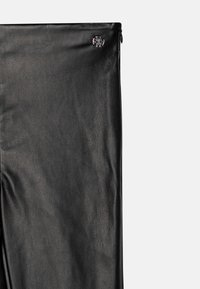 Black leather pants with a textured finish, featuring a zip closure on one side and a silver metal accent near the waist.