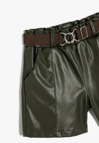 Grønne faux læder shorts med et brunt stoffe bælte. Har en høj talje, to sidelommer og plisseret design.
