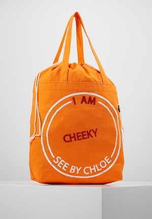 Bolso tote de color naranja brillante con asas largas, cierre con cordón y texto en rojo y blanco que dice "I AM CHEEKY SEE BY CHLOE" en la parte delantera.