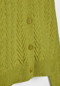 Grüne Strickjacke mit Zickzackmuster, ausgestattet mit fünf passenden Knöpfen und ribbeligen Bündchen, die einen strukturierten Look erzeugen.