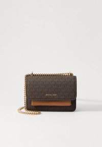 Mala tiracolo padrão castanho com alça de corrente dourada, apresentando um fecho de aba e um painel frontal castanho contrastante. Marca Michael Kors visível.