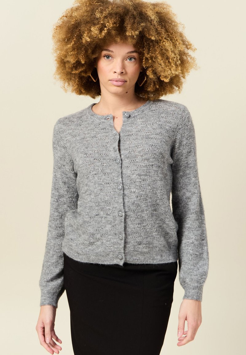 Grauer gestrickter Cardigan mit rundem Ausschnitt, langen Ärmeln und Knopfverschluss. Die Textur ist weich mit einem subtilen Muster.