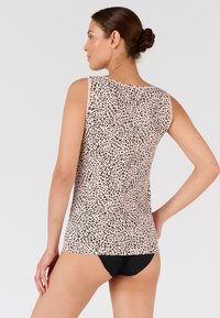 Leopardenmuster-Tanktop, hellrosa mit schwarzen Punkten, ärmelloses Design, glattes Material und runder Ausschnitt, kombiniert mit schwarzen Unterteilen.