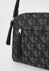 Black patterned shoulder bag made of textured fabric, featuring a sleek design, leather accents, and a silver brand logo detail.