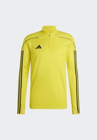 Pull-over athlétique jaune avec une fermeture zippée quart, des rayures noires le long des manches et le logo adidas sur la poitrine gauche, fabriqué en tissu qui évacue l'humidité.
