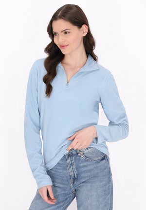 Pulover din fleece de culoare albastru deschis, cu guler cu fermoar, mâneci lungi și textură moale, asortat cu blugi din denim albastru.