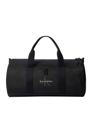 Czarny cylindryczny torba podróżna z podwójnymi uchwytami, zamkiem błyskawicznym oraz logo Calvin Klein na przedniej kieszeni.
