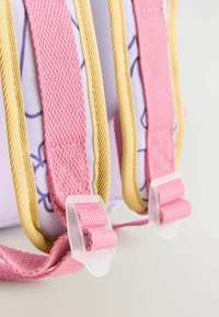 Rosa och gula remmar med en texturerad yta, med plastbeslag. Bakgrunden är i en ljus, neutral färg som framhäver remmarnas design.