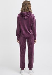 Pluchen, tweedelig lounge-outfit in diep paars; sweatshirt met trekkoord, relaxte pasvorm en bijpassende tapered broek met elastische boorden.