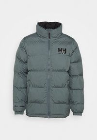 Kurtka puchowa w stonowanej zieleni, z wysokim kołnierzem, zamkiem błyskawicznym i poziomym pikowaniem. Czarne logo na piersi i rękawie.