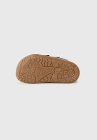 Semelle de chaussure d'enfant avec un motif de semelle texturé, le nom de la marque « Froddo Barefoot » et le numéro de taille 23 visibles sur la semelle en caoutchouc.
