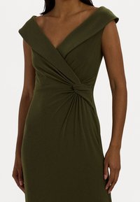 Olive green dress made of stretchy fabric. Features a deep V-neckline, wide shoulder straps, and a twist detail at the waist.