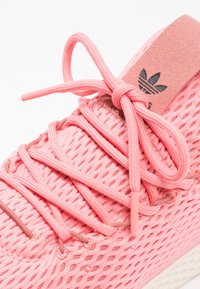 Rosa sneakers med en texturerad mesh-övre, platta snören och en mjuk, vadderad tunga med logodetalj och en upphöjd sula.