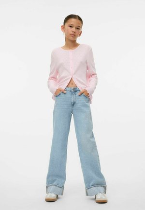 Gilet côtelé rose clair avec des boutons et des poignets froncés, associé à un jean large taille haute bleu clair et des baskets blanches.