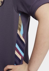 Maglietta sportiva viola scuro con tessuto testurizzato, caratterizzata da accenti laterali a strisce multicolori in blu, beige, bordeaux e blu navy.