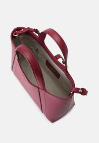 Bolsa de mão em couro vermelho com duas alças, design estruturado e interior forrado a tecido. Apresenta um fecho dourado e uma etiqueta da marca no interior.