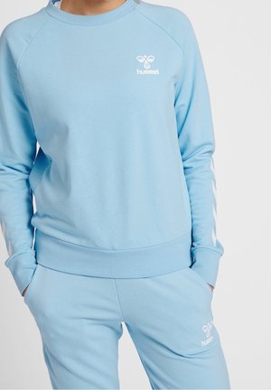 Jasnoniebieska bluza z logo, z okrągłym dekoltem i raglanowymi rękawami. Do kompletu dopasowane spodnie dresowe o gładkiej fakturze i elastycznym pasie.