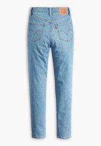 Jean en denim bleu clair taille haute, deux poches arrière, patch en cuir marron de la marque et étiquette rouge sur la couture de la poche droite.