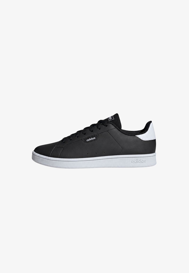 Baskets basses noires Adidas avec talon et semelle blancs, design à lacets et logo Adidas sur le côté et la languette.