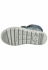 Suela de goma gris con surcos texturizados y un detalle en forma de estrella. La parte superior presenta tela azul con acentos verdes y tiras de Velcro para el cierre.