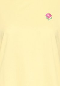 Tissu jaune clair avec petite fleur rose pixellisée et tige verte brodée en haut à droite.