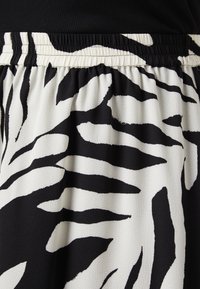 Tissu à motifs zèbres noir et blanc avec une surface texturée, doté d'une taille élastique pour plus de confort.