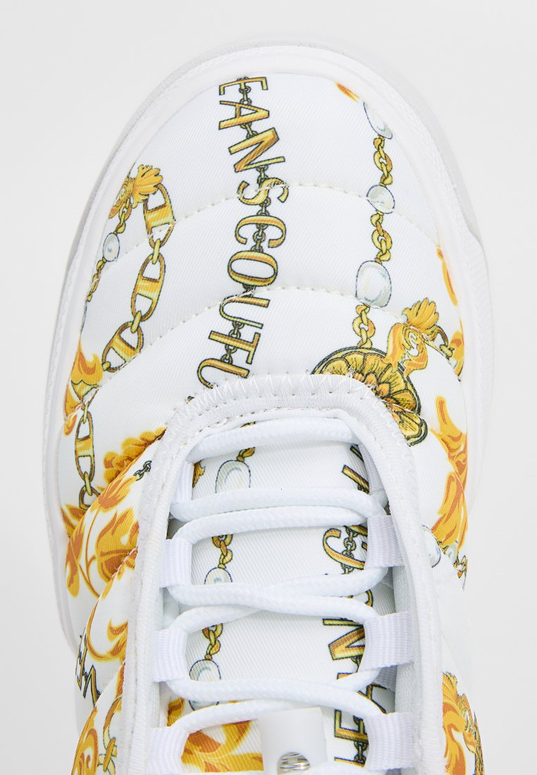 Weißer Sneaker mit gelber und goldener Kette sowie Blumenmuster und dem Text "FANSCOUT" auf dem Obermaterial nahe den Schnürsenkeln.