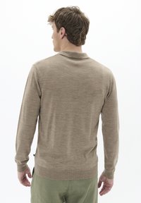 Beige polo shirt met lange mouwen, van een gestructureerde brei, met ribgebreide manchetten en een platte kraag. Weergave toont de achterkant met een rechte zoom en subtiele branding.