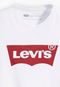 White cotton t-shirt featuring a large red Levi's logo in a curved banner design. Short sleeves and a crew neck finish.