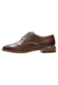 Chaussure Oxford en cuir marron au design élégant, bout rond, cinq œillets, et petit talon en bois avec un accent transparent. Texture lisse.