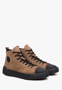 Bruine suède hoge sneakers met zwarte rubberen neus- en zool, voorzien van zwarte veters en oogjes, en een reliëf logo detail.