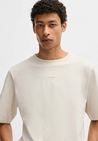 Lichtbeige crew neck t-shirt met korte mouwen, zachte stof en een subtiele reliëf "BOSS" logo op de borst.