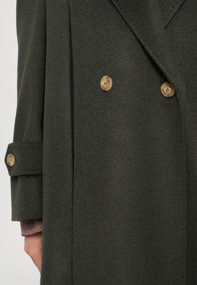 Manteau double-breasted vert foncé en tissu texturé, avec des boutons dorés et des détails aux poignets. Fini lisse avec un design structuré.